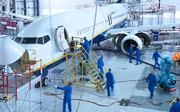 Group of nine airplane technicians wearing blue uniforms working on a plane